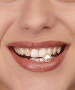 Lächelnde Frau mit einer weißen Perle zwischen den Zähnen